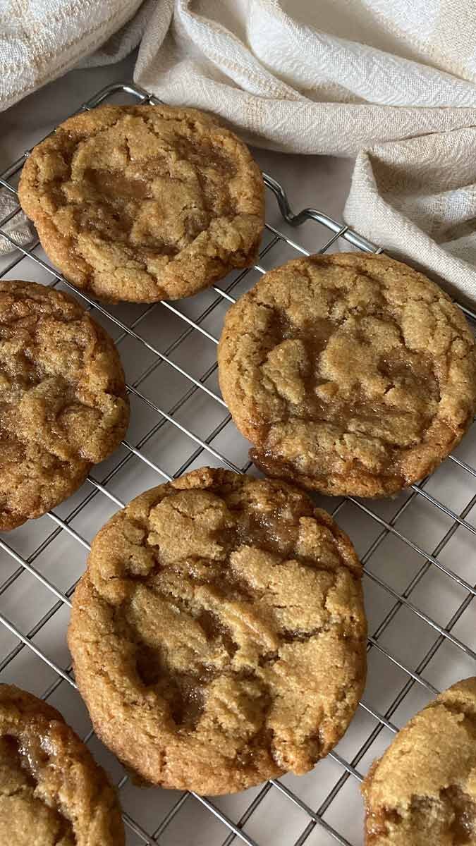 easy homemade chewy brown butter toffee cookies on a cooling rack surrounded by linen