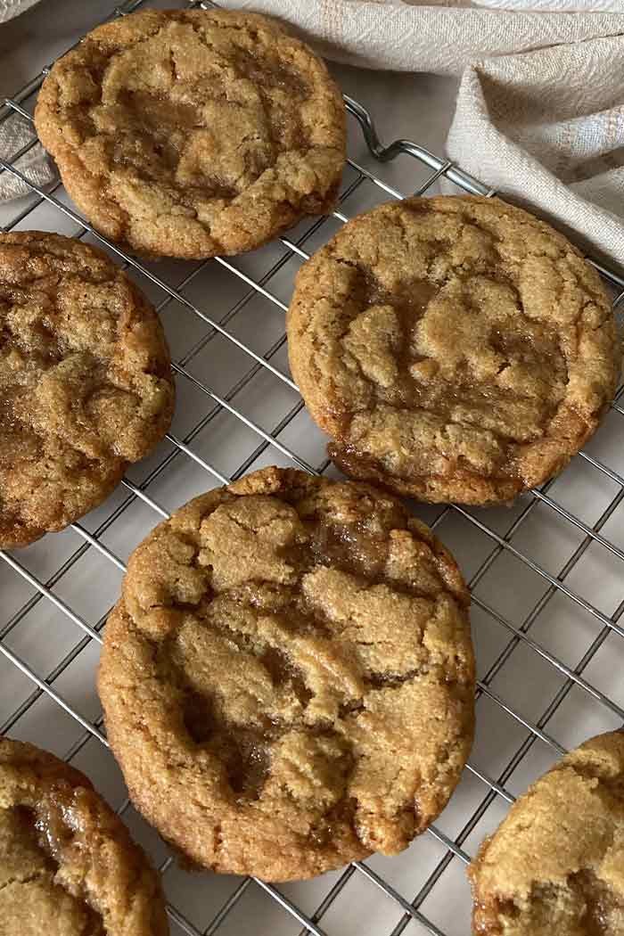 easy homemade chewy brown butter toffee cookies on a cooling rack surrounded by linen