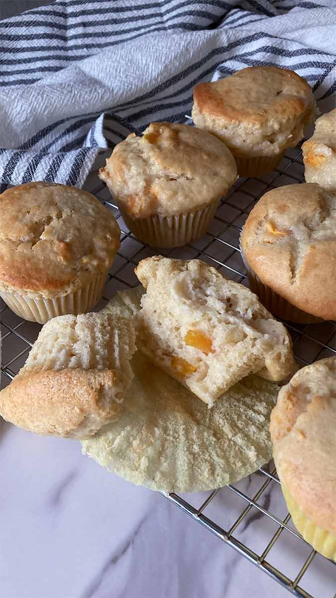 half of a peaches and cream muffin showing the tender crumb surrounded by more muffins