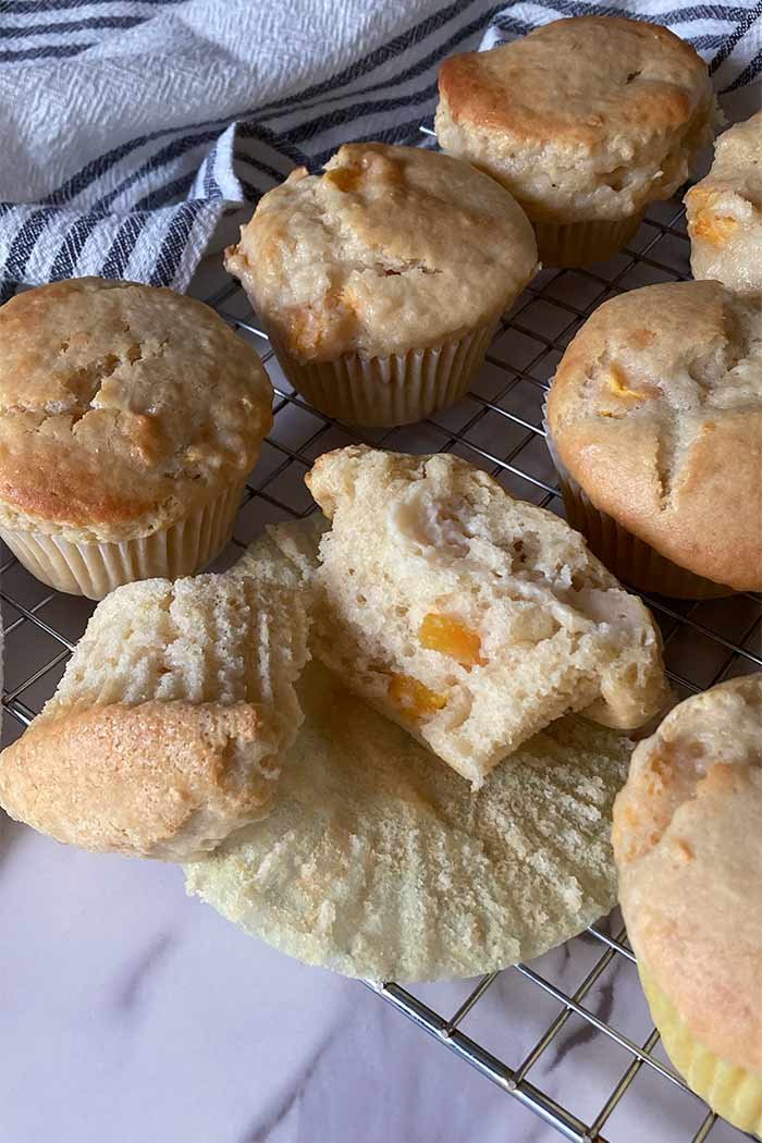 half of a peaches and cream muffin showing the tender crumb surrounded by more muffins