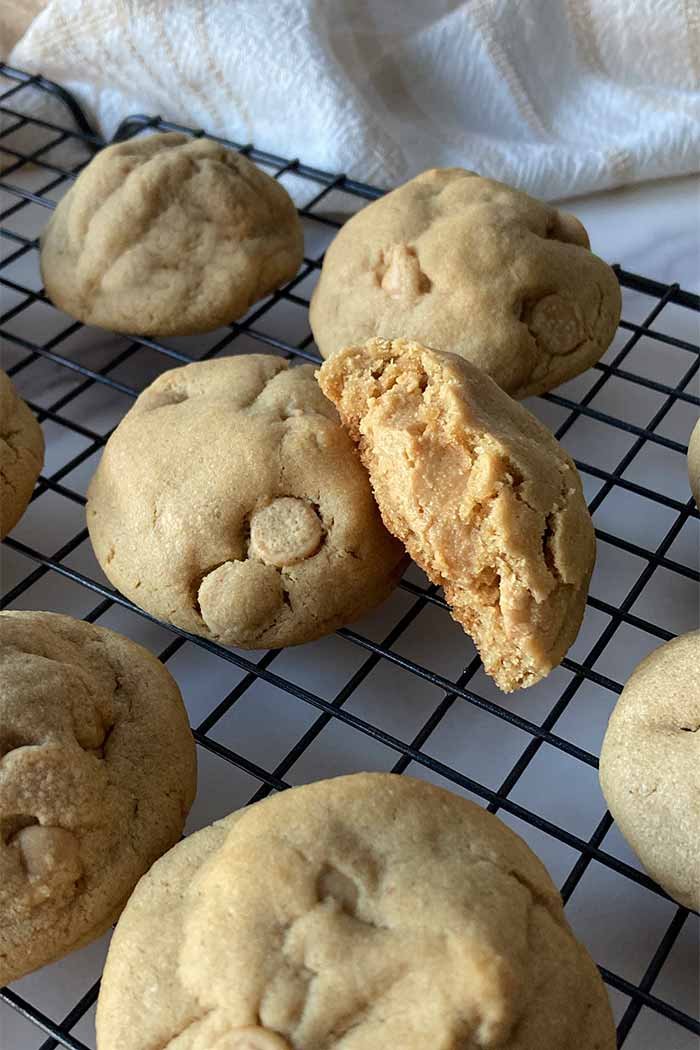 ultimate peanut butter cookies on a cooling rack, one broken open to show the peanut butter filled center