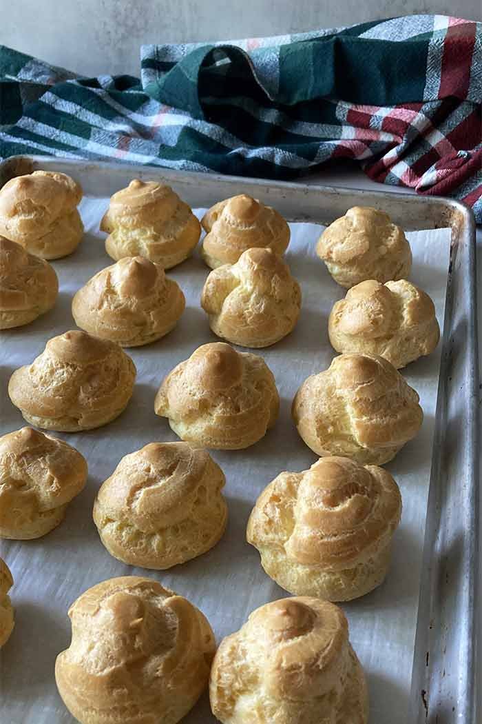 homemade cream puffs on a cookie sheet