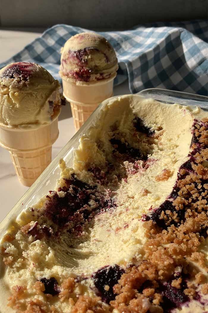 homemade blueberry muffin ice cream with streusel, scooped to show texture, sitting in front of two ice cream cones