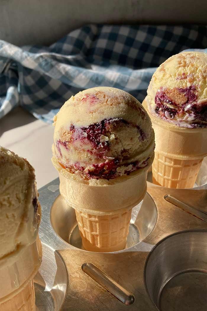three cones filled with homemade blueberry streusel muffin ice cream sitting in a muffin tin