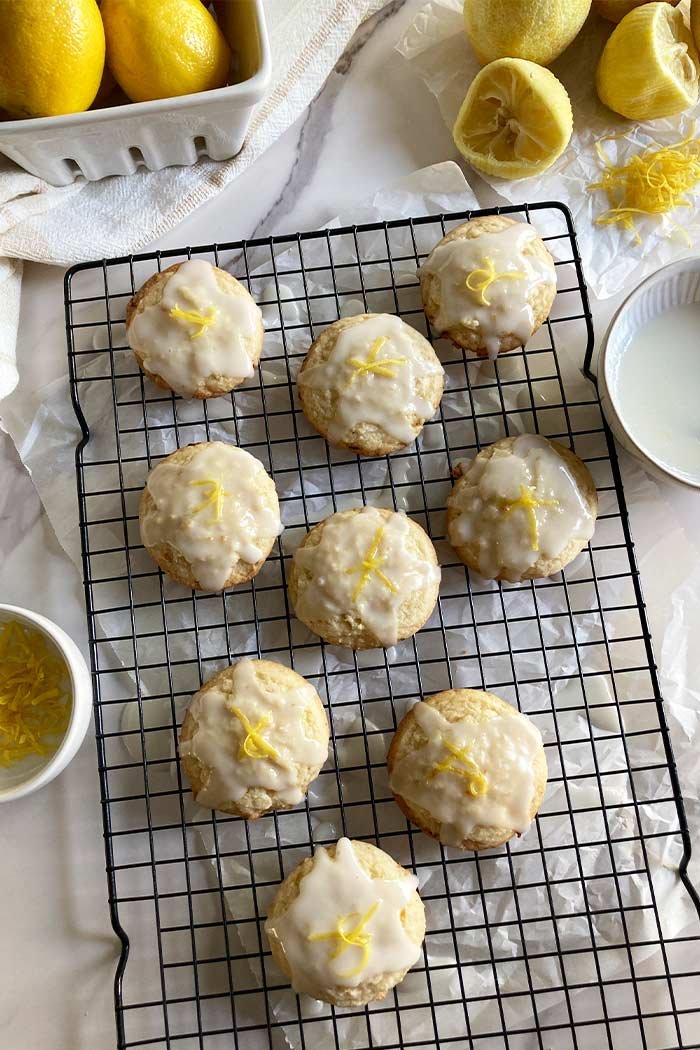 homemade lemon cookies topped with lemon glaze and lemon zest on a cooling rack