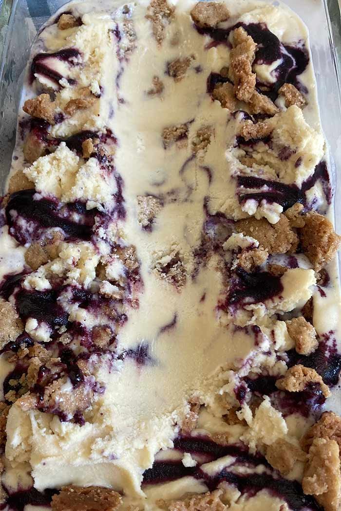 container of homemade blueberry streusel muffin ice cream, scooped to show texture