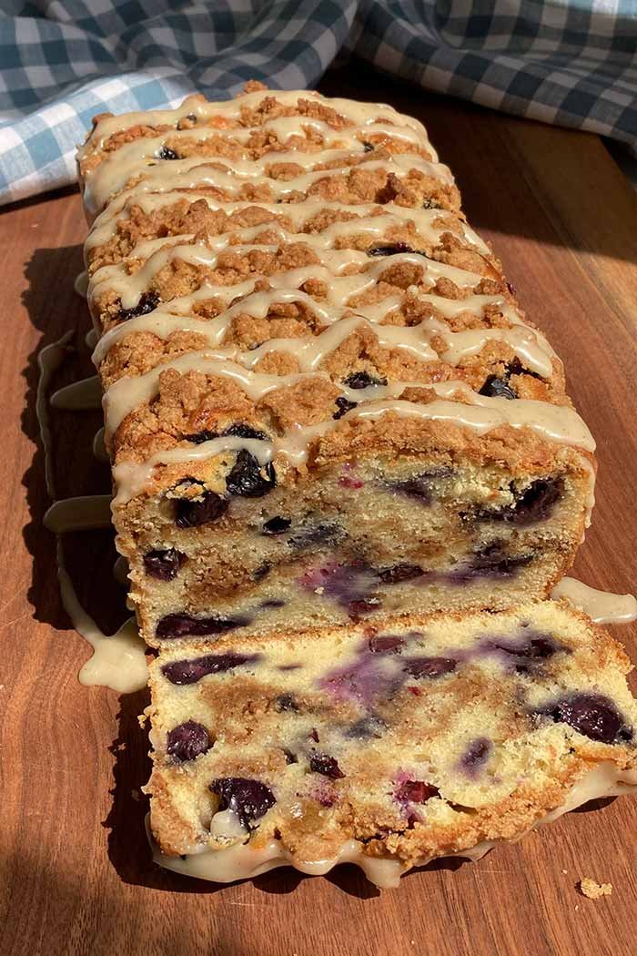 blueberry streusel loaf cake drizzled with glaze, sliced to show the blueberries and cinnamon swirl inside