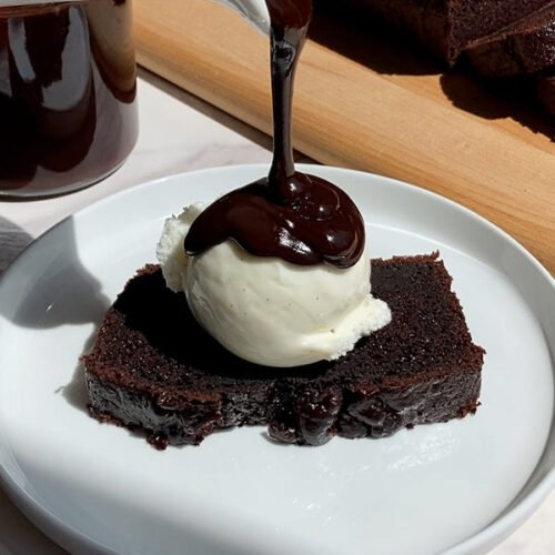 brown butter espresso hot fudge pouring over a slice of chocolate espresso loaf cake with a scoop of vanilla ice cream