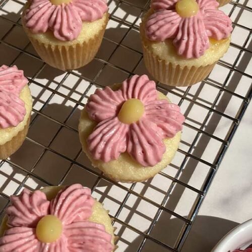 zoomed in on mini raspberry lemonade cupcakes decorated like pink flowers on a cooling rack