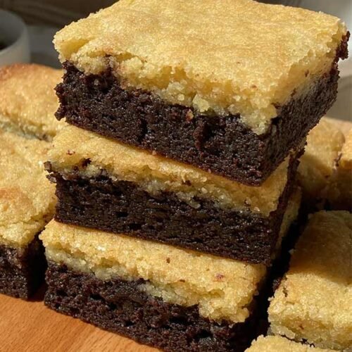 stack of brownies topped with a layer of almond frangipane on a wooden cutting board