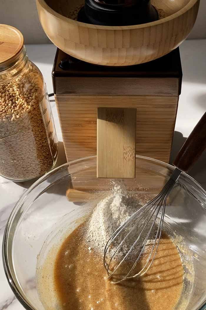 a grain mill grinding wheat berries into whole wheat flour into a mixing bowl for cookies