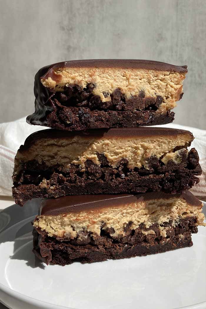 stack of three slices of peanut butter mousse brownie crunch cake on a plate showing off the varying textures in each layer